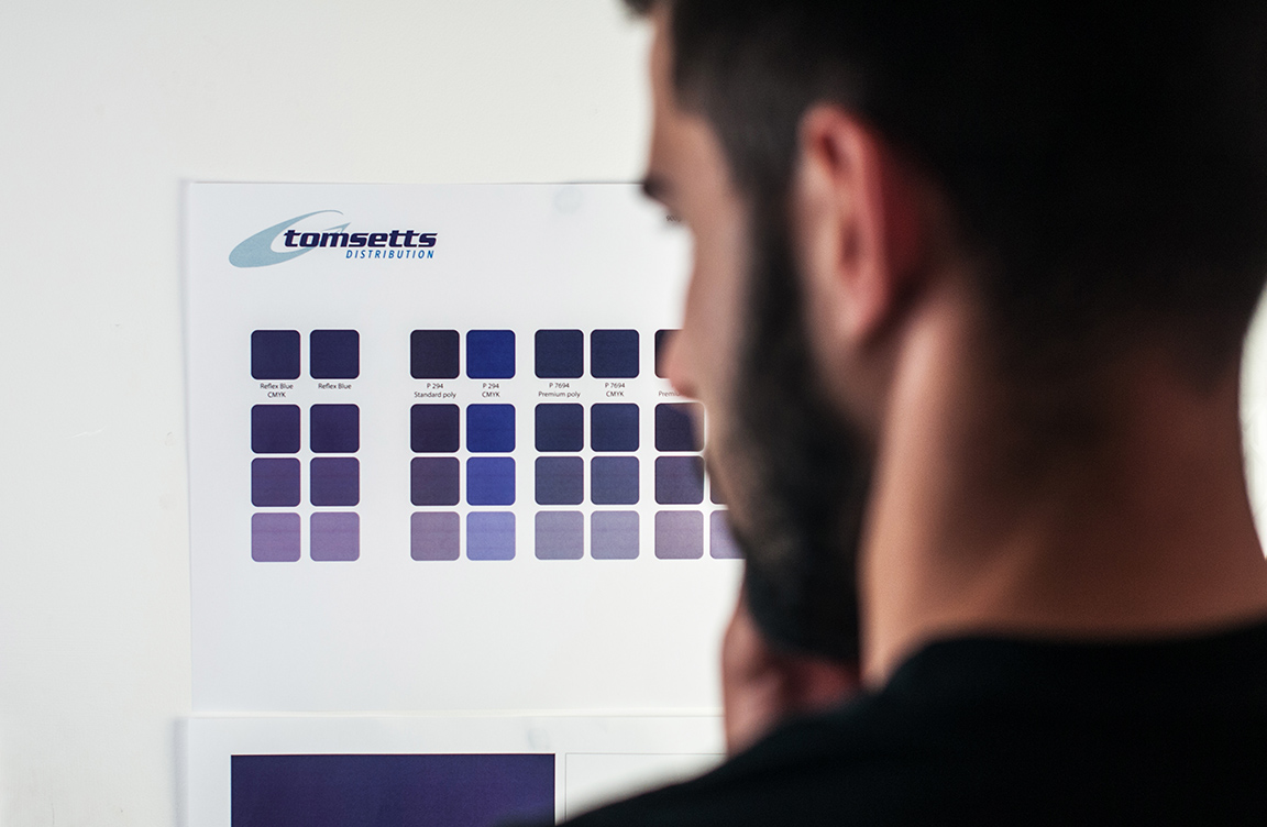 Bearded man looking at a colour chart on the wall.