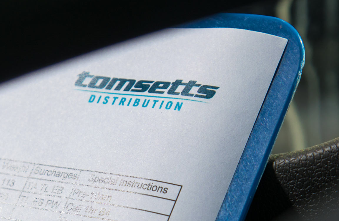 The Tomsetts logo on a page on a clipboard.